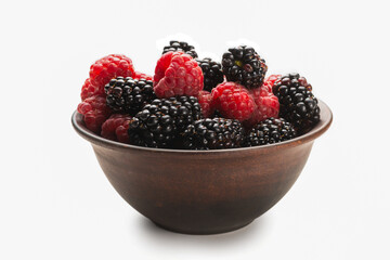 Raspberry, blackberry and mint leaf in ceramic brown bowl isolated on white