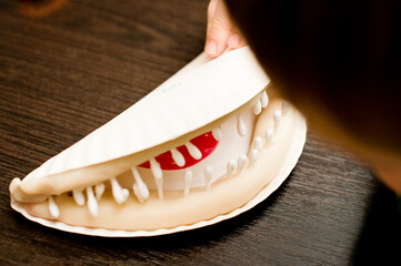 DIY play oral hygiene. boy making mouth with teeth from paper plate and ear buds. reminding Carnivorous Plant.