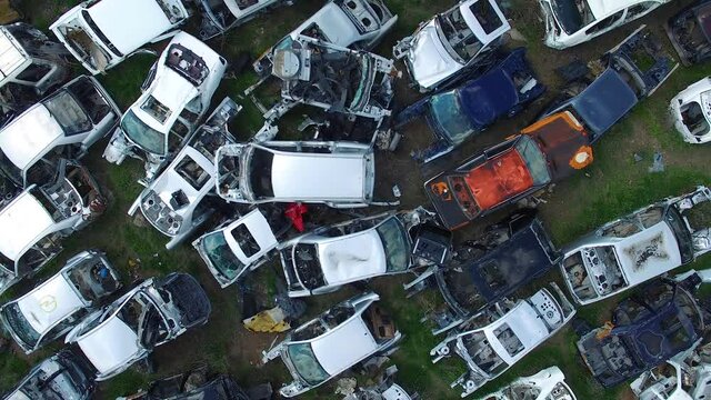Top view car dump. Drones's camera slowly move up from damaged cars. Different, many old, rusty, abandoned cars.