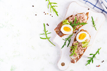 Toasts with tuna. Italian bruschetta sandwiches with canned tuna, egg and cucumber. Top view, flat lay, copy space