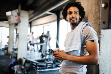 Young muscular man using mobile phone at the gym in exercise break