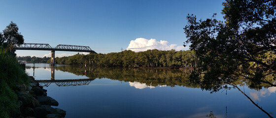 beautiful early morning view of river with reflections of clear blue sky, bridge and trees on water, Parramatta river, Rydalmere, New South Wales, Australia