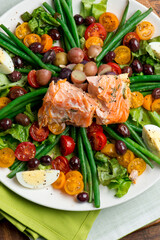 Nicoise salad. Romaine, cherry tomatoes hard boiled eggs, baby purple potatoes. green beans and grilled salmon tossed with olive oil and salt and pepper