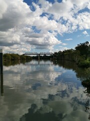 Obraz premium beautiful early morning view of river with reflections of blue sky, clouds, bridge and trees on water, Parramatta river, Rydalmere, New South Wales, Australia