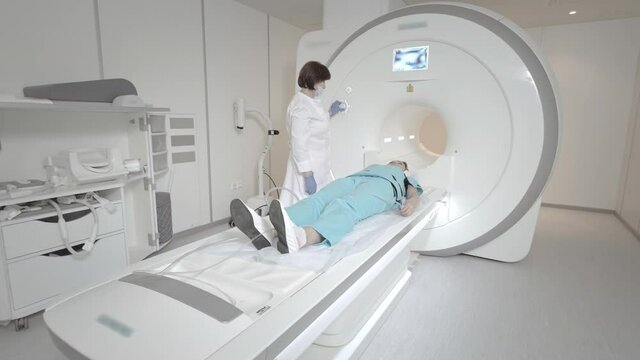 The doctor performs an MRI scan for a patient at the clinic. The girl lies in the MRI device. Magnetic resonance imaging in the study of the human body. Modern technologies in medicine.