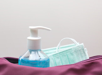 Alcohol gel bottle and surgical mask in handbag. Concept for new normal items for prevention of Covid-19 disease