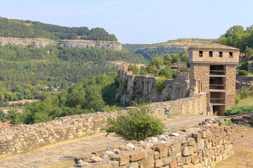 Ancient stone walls and towers against the background of low hills in the sun