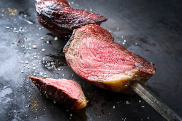 Barbecue dry aged wagyu Brazilian picanha from the sirloin cap of rump beef sliced and offered as close-up on a skewer on a rustic old board with copy space