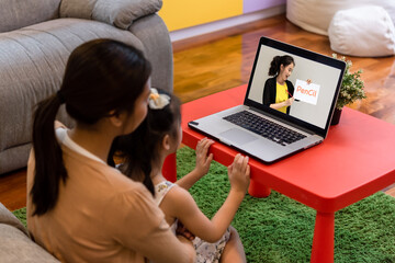 Mother and daughter sit in front of. a labtop study attending online course together at home