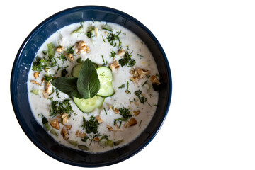 Blue plate with tarator isolated on white background. Cold soup with cucumbers.