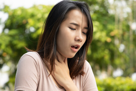 sick asian woman having sore throat; concept of sickness with coughing, hiccupping, choking, acid reflux