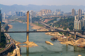 Chongqing, China - March 20, 2018: Top view of the  Jialing River in the Chinese city of Chongqing. Bridges, city blocks, mountains. Sunny day in the metropolis.