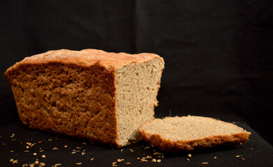 Freshly baked homemade bread on a dark background. Sliced ​​chunk.
