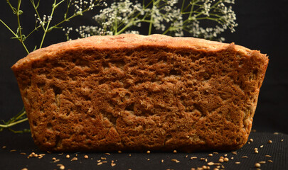 A loaf of fresh homemade bread. Sourdough homemade cakes. In the background are flowers of the Tumbleweed. Dark background