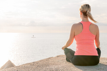 Fototapeta na wymiar back of a blonde woman practicing yoga at sunrise