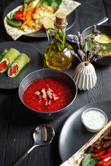 Various culinary dishes on a dark wooden table. Exquisite restaurant serve on dark dishes