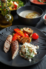 Various culinary dishes on a dark wooden table. Exquisite restaurant serve on dark dishes