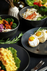 Various culinary dishes on a dark wooden table. Exquisite restaurant serve on dark dishes