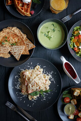 Various culinary dishes on a dark wooden table. Exquisite restaurant serve on dark dishes