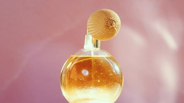 Luxury golden perfume bottle and shining light flares on pink background, glamorous fragrance scent as perfumery product for cosmetic and beauty brand, stock footage