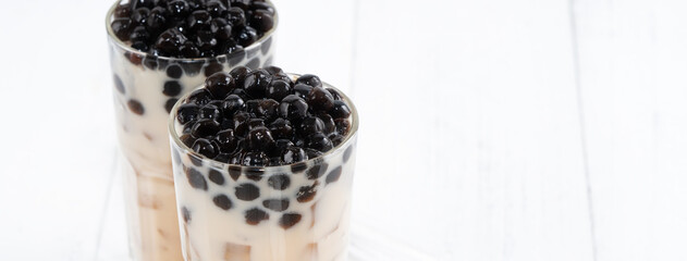 Fototapeta na wymiar Bubble milk tea with tapioca pearl topping, famous Taiwanese drink on white wooden table background in drinking glass, close up, copy space