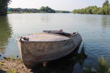 Naklejka na ściany i meble an old boat with oars on the river Bank in summer