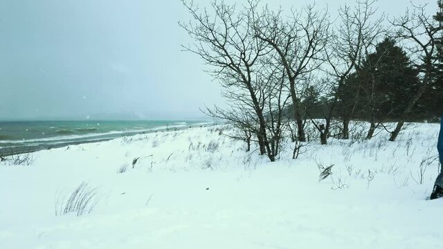 Man walking on frozen lakeshore.  Natural environment fresh water winter scene in Michigan.  Dreary and lonely.