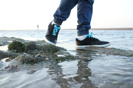 Young Man walks on Beach Rocks
