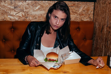 Young Woman With a Hamburger in a Cafe