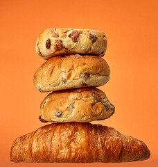 Buns and croissant in a studio setting, isolated on orange