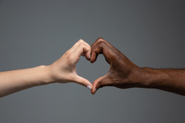 Love heart gesture. Racial tolerance. Respect social unity. African and caucasian hands gesturing...