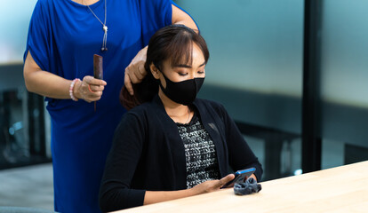 Young Asian woman at hairdresser salon wearing surgical protective face mask. New normal and social distancing concept