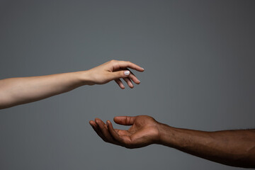 Touch of God. Racial tolerance. Respect social unity. African and caucasian hands gesturing on gray...