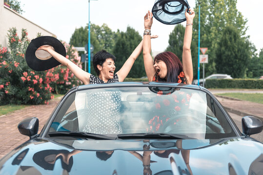 Amiche donne alla guida di un'auto convertibile godendo le vacanze divertendosi sulla strada.