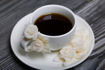 A cup of black coffee in a vintage cup decorated with polymer clay roses. Cup on a saucer.