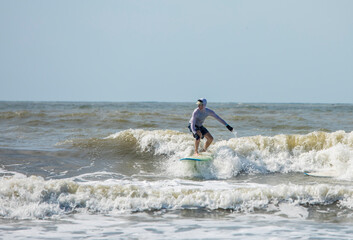 Middle aged man surfs on a longboard in the Atlantic.