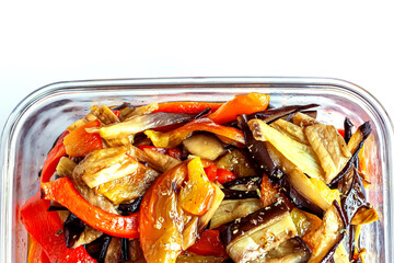 Grilled eggplants and sweet red peppers appetizer in the glass bowl on thw white background. Healthy eating, seasonal colorful vegetables concept. Top view. Space for text.