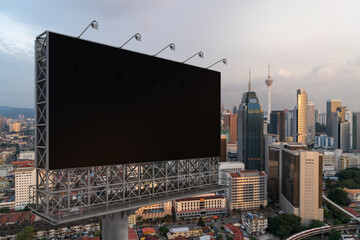 Blank black road billboard with KL cityscape background at sunset. Street advertising poster, mock up, 3D rendering. Side view. The concept of marketing communication to promote or sell idea.