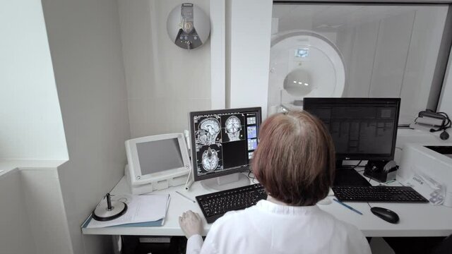 Doctor technician monitors an MRI scan. Magnetic resonance imaging in the study of the human body. The specialist is looking at the monitor in the laboratory.