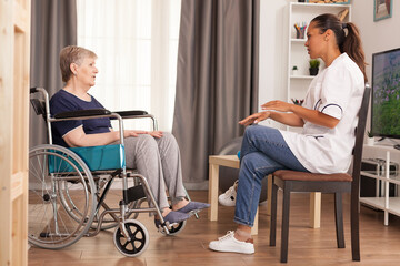 Nurse checking on retired handicapped old woman. Disabled handicapped old person recovering...