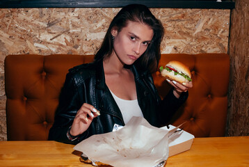 Hungry Young Fashion Lady Eating a Hamburger in a Cafe