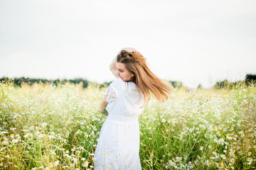 Happy girl on the camomile field, summer sunset. in a white dress. running and spinning, the wind in my hair, life style. freedom concept and hot summer