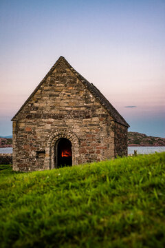 Candles Burn Inside St Oran's Chapel By the Sea at Dusk on the Isle of Iona Scotland