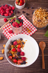 Yogurt with fresh berries, muesli oatmeal granola on the wooden table. Healthy breakfast concept.
