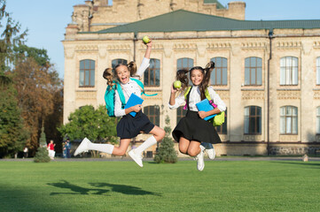 Fototapeta premium Driven and energetic. Energetic children in midair outdoors. School girls in energetic jump. Back to school fashion. School snack. Energetic diet. Food giving energy. Healthy and active