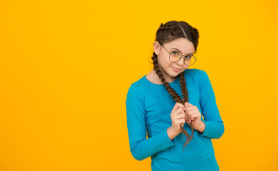 Fototapeta na wymiar she is shy. Positive emotions. kid wear glasses because of poor eyesight. Portrait of happy girl in glasses. beautiful smiling girl with fashionable hairstyle. smart looking kid yellow background