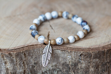 Agate mineral stone beads bracelet with feather pendant on wooden background
