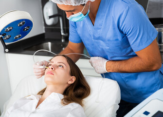 Portrait of female patient during cosmetology procedure in beauty clinic, getting carbon dioxide...