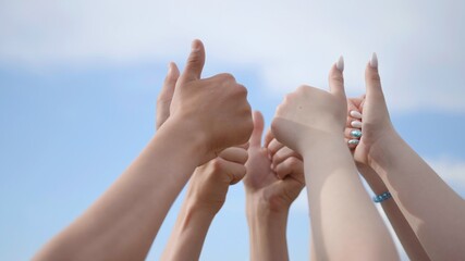 A group of friends raise their hands with their fingers up.