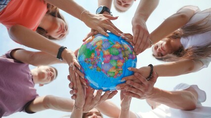 The concept of saving the world. A group of friends hold the world globe in their hands.